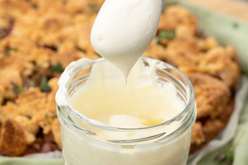 Potje met crÃ¨me fraÃ®che waar met een lepel iets uitgeschept wordt